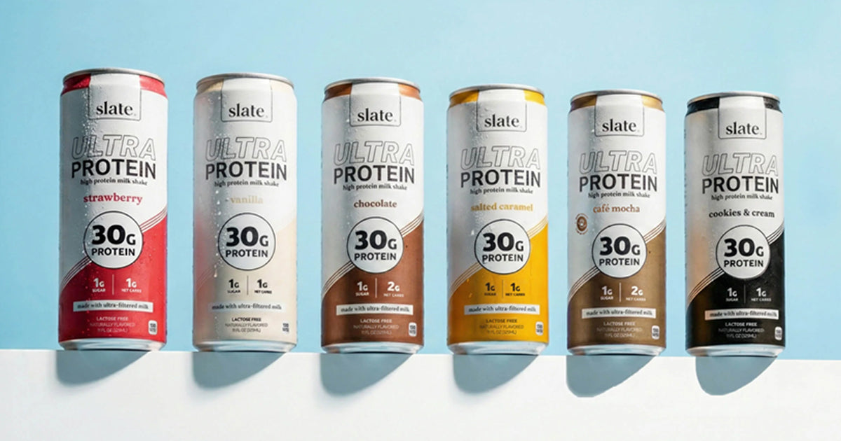 Row of six Slate Ultra Protein milkshake cans on a blue background